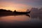 Colorful orange blue sky over the sea at sunrise. Morning sky with clouds, smooth waves and traditional fishing boat silhouette.