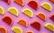 Colorful oval citrus jelly candies pattern on a pink background. Yellow, pink, red, orange round shaped marmalade