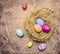 Colorful, painted decorative Easter eggs in the nest wooden rustic background top view close up