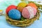 Colorful painted eggs in a nest of twigs of willow on a light background.