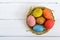 Colorful painted eggs in a nest of twigs of willow on a light background.