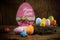 Colorful painted happy easter greeting card eggs in birds nest basket on rustic wooden background