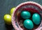 Colorful painted marble shiny Easter eggs in a basket with delicate feathers close-up. Nest with straw - Easter decoration on the