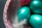 Colorful painted marble shiny Easter eggs in a basket with delicate feathers close-up. Nest with straw - Easter decoration on the