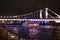 Colorful panorama of the night city with neon lights. Bridge over the river against the background of historic buildings at night