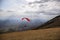 A colorful paraglider flying over Monte Cucco Umbria, Italy, with some faint sunrays.