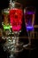 Colorful party glasses, red, blue and green, filled with champagne, cava or prosecco, on a dark and black background.