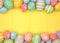 Colorful pastel Easter Egg double border against a yellow wood background