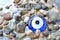 Colorful pebbles on the beach with turkish evil eye glass bead. Background with color stones on the sea and amulet