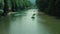 Colorful pedal catamarans and people in a beautiful river with green-colored water. A dense forest grows along the banks