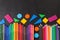 Colorful pencils in row and geometric figures on the black school chalkboard