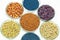 Colorful pesticide-treated rapeseed, sunflower, wheat, pea, soy, and corn seeds in a petri dish in the lab