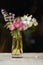 Colorful picturesque bouquet of spring flowers in vase on dark background