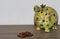 A colorful piggy bank with a money heap of cent coins isolated on a wooden underground and white background