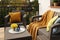 Colorful pillows, soft blanket and yellow chrysanthemum flowers on rattan garden furniture outdoors