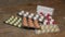 Colorful pills and capsules in blisters on an old wooden table. Orange pills in focus.