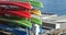 Colorful plastic canoes stacked at a dock in a beautiful marina