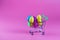 Colorful Plastic Easter Eggs shopping cart on pink background