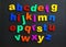 Colorful plastic magnetic letters on black background, top view.