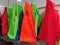 Colorful plastic shopping bags hang on supermarket shelf.