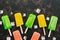 Colorful popsicles, pink, yellow, green.Top view, dark background, copy space.