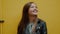 Colorful portrait of young happy woman looking up with smile against yellow wall