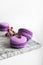 Colorful purple macaroons with flower on a light grey background. Food photo. Food photography. Simplicity. Minimalism.