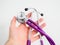 Colorful purple stethoscope in hand of doctor on white background isolation. Medicine.