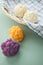 Colorful rainbow cauliflower in purple, orange and white on kitchen towel with knife in basket on pastel mint green background