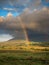 Colorful rainbow in a green field, Dramatic sky, Connemara loop, Ireland. Vertical image