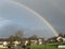 Colorful rainbow over small city houses, Green lawn