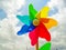 Colorful rainbow pinwheel in front of a beautiful cloud filled sky.