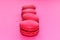 Colorful raspberry, strawberry macaroons on pink background, French heart biscuits