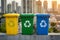 Colorful recycling bins against a cityscape background.