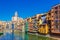 Colorful red, orange and yellow houses and bridge through river Onyar in Girona, Catalonia, Spain. Scenic ancient town. Famous