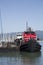 Colorful red tugboat docked at a wood pier