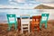Colorful retro wooden chairs and a table lined up on the beach at the seaside