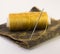 Colorful roll of thread on a piece of leather with a needle.