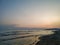 Colorful romantic sky during evening on a sandy beach with a view on wavy sea during sunset