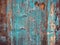 Colorful rough wood texture: old rustic house wall covered with bright turquoise peeling paint.