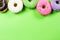 Colorful round donuts on green background. Flat lay, top view.