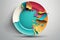 Colorful round plate with splashes on grey background