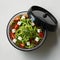 Colorful salad with noodles, tomatoes, cheese cubes, herbs in round transparent container