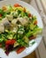 Colorful salad, sliced herring, various types of lettuce, sliced tomatoes, avocado, pieces of feta cheese, healthy food on a plate