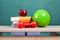 Colorful school accessories (apple, books, ball) on table