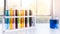 Colorful science test tube in plastic rack with blue water in beaker on white top table