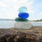 Colorful sea glass pyramid on beach rock with seascape background. Seaglass stack beach combing