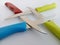 Colorful sharp steak knives arranged in a square on a white background