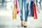 Colorful shopping bags in the hands of a shoppers woman and her legs jeans and shoes