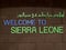 Colorful Sierra Leone Sign in English and Arabic with black background, an African Nation